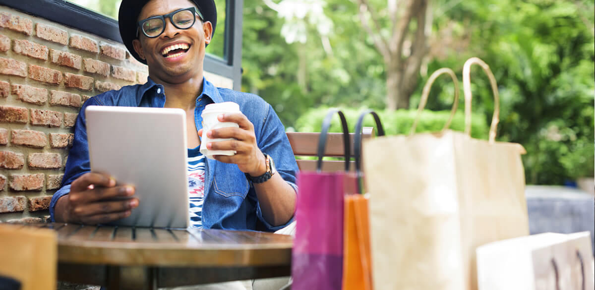 Happy shopper drinking coffee and browsing tablet